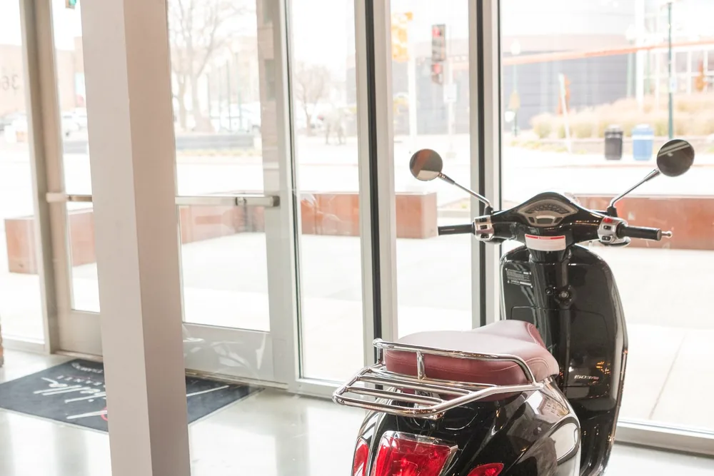 A black Vespa parked inside the window at Maribella